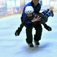 Тренер на льду с ребенком на руках